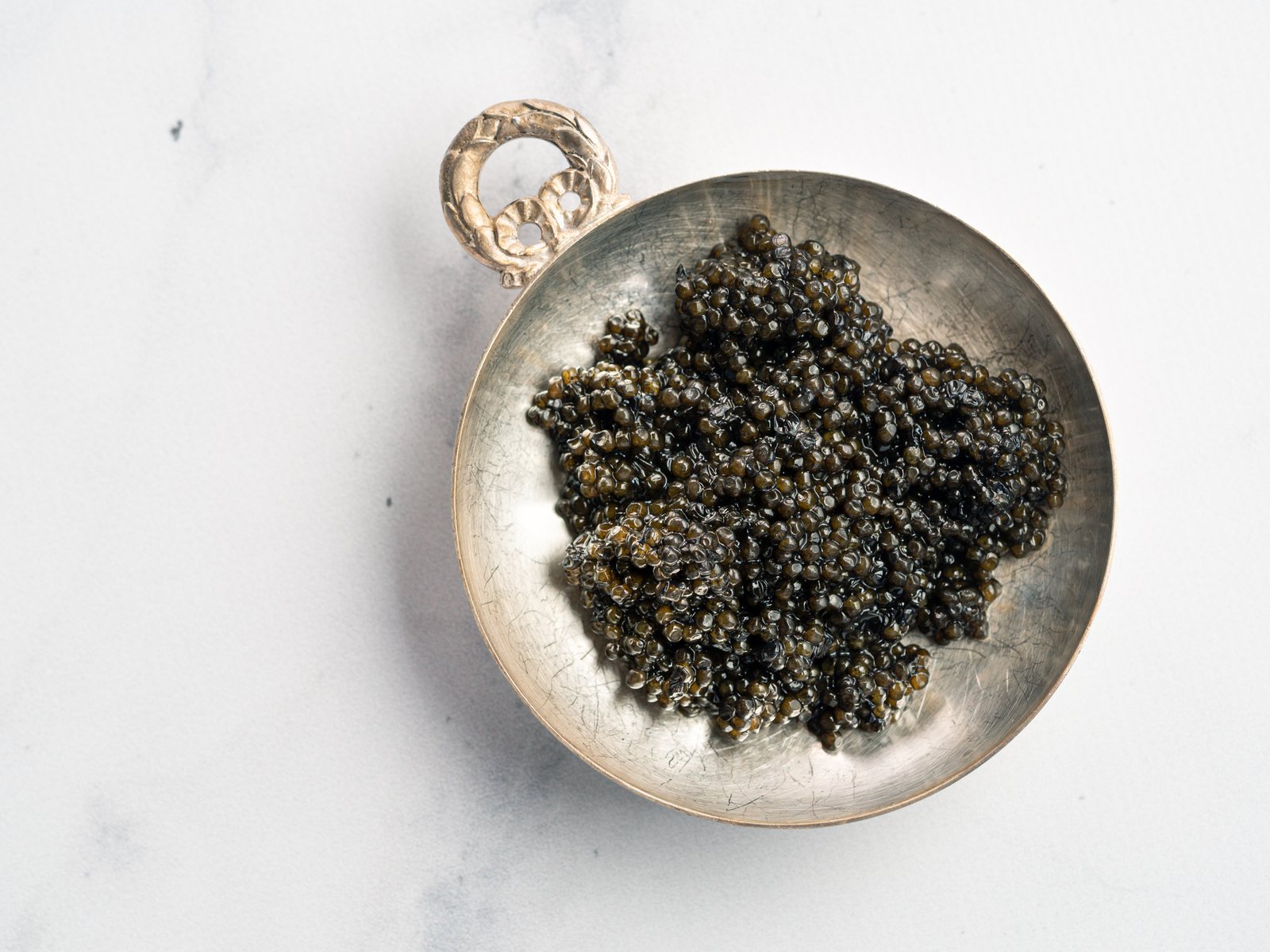 Bowl of black caviar on white marble