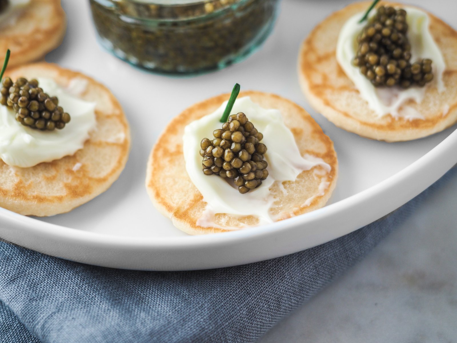 Closeup of a biscuit with cream and caviar on top on a round white plate
